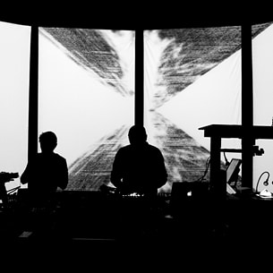 Photo noir et blanc de 2 artistes de la Compagnie Organic Orchestra sur scène devant un écran circulaire en 4 parties