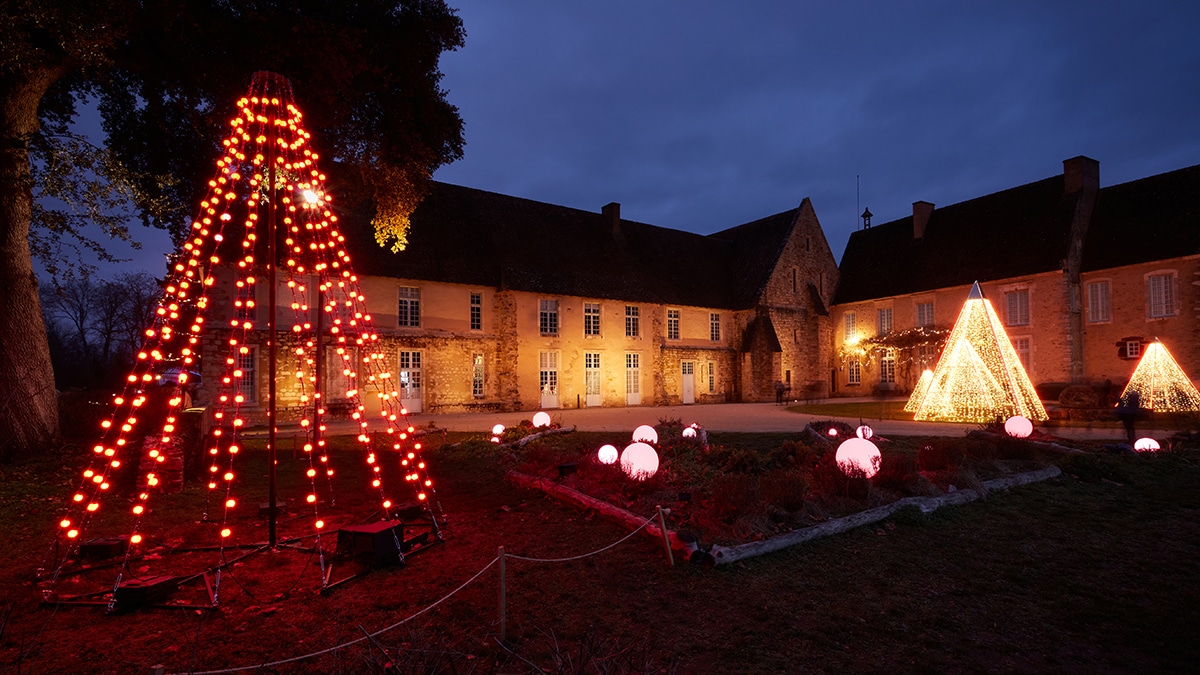 Installation de guirlandes lumineuses évoquant la forme d’un sapin dans la cours du logis d’une abbaye