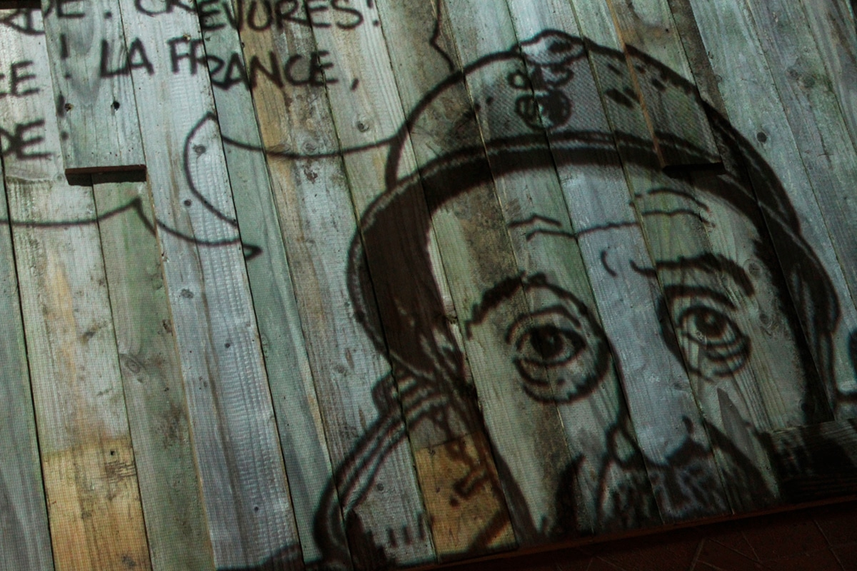 Portrait d’un poilu dessiné par Tardi et projeté sur une palissade en bois