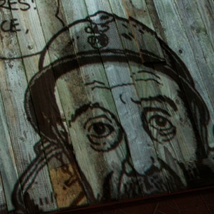 Portrait d’un poilu dessiné par Tardi et projeté sur une palissade en bois