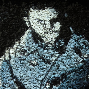 Portrait d’un dessin de Tardi de soldat français de la première guerre mondiale projeté sur un parterre de cailloux