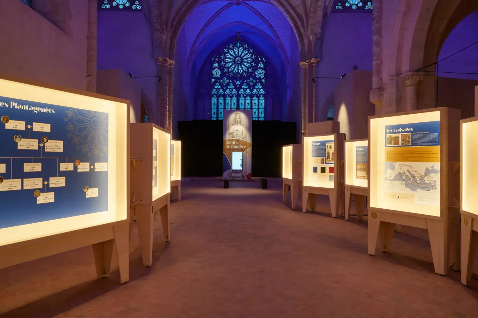 À la rencontre d'une reine : panneaux d'exposition lumineux alignés dans la nef, rosace en fond
